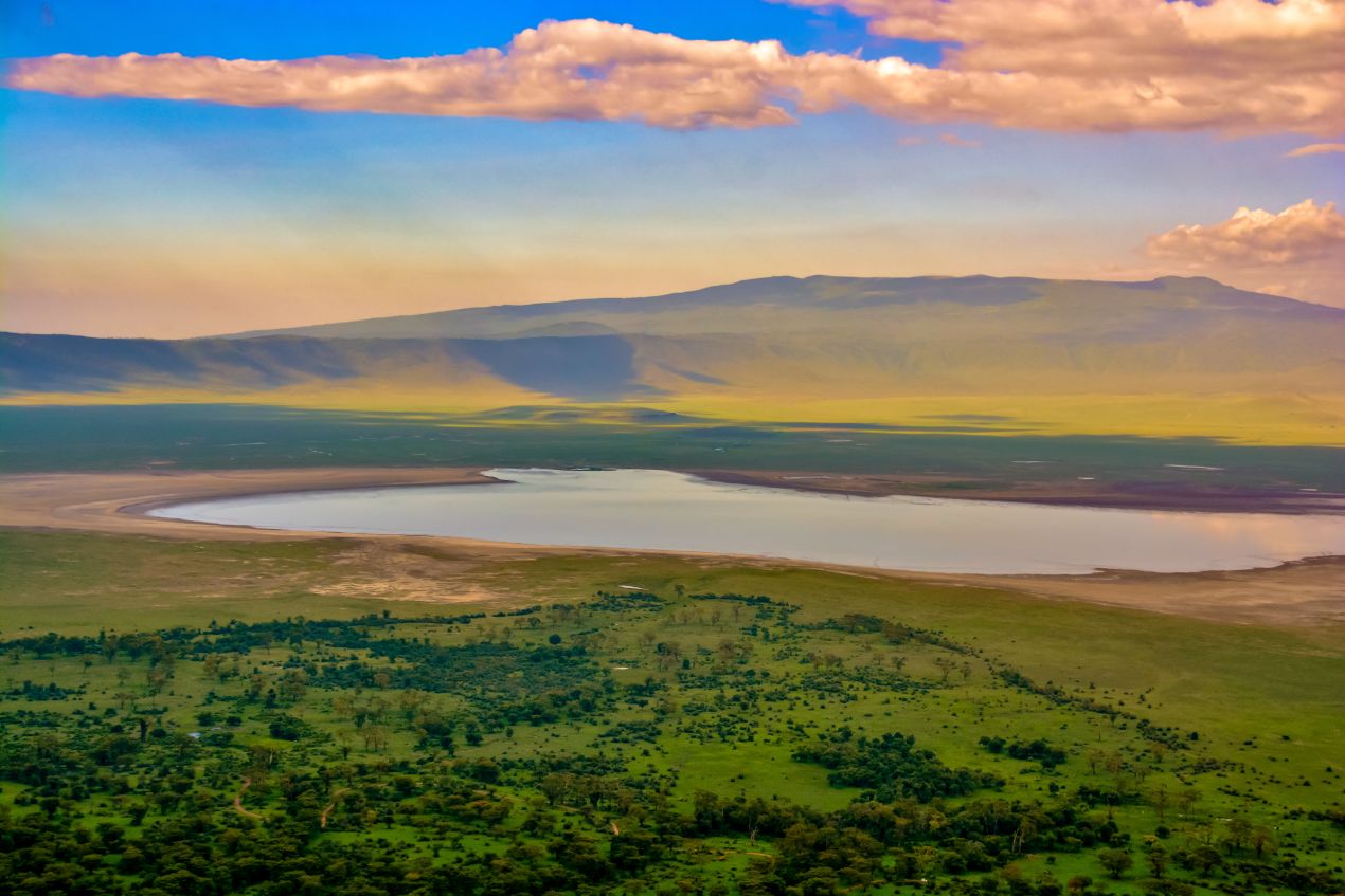 Blick auf den Ngorongoro-Krater mit seinem See und der grünen Savanne, ein einzigartiger Ort voller Tierwelt und ein Highlight jeder Tansania Safari.